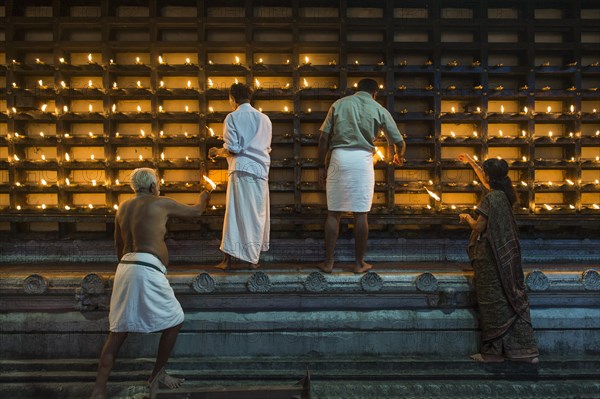 Oil lamps being lit in niches on the outer wall of the temple for the Hindu fire ceremony Aarti