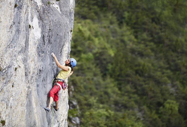Freeclimber with helmet climbing on a rock face