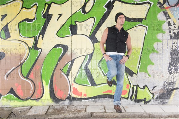 Portrait of a man standing in front of wall covered with graffiti