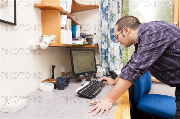 GP doctor using a computer in his surgery