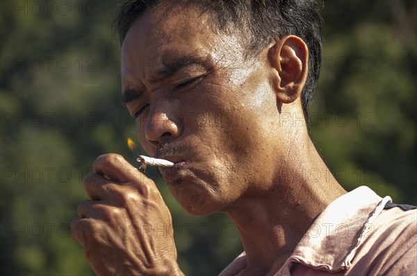 Man from the Shan or Thai Yai ethnic minority is lighting a cigarette