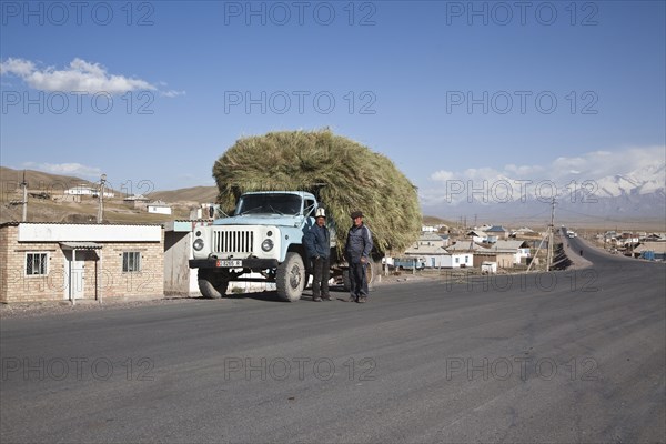 Kyrgyz men standing next to a fully loaded truck