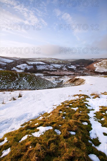 View of lingering snow on moorland hills and fields in late afternoon sunshine