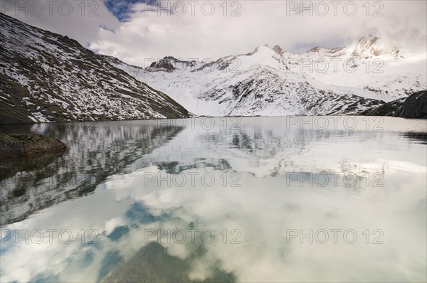 Foggy atmosphere at Unterer Gerlossee lake with mountains Wildgerlosspitze