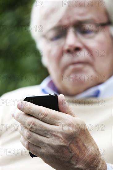 Senior holding a smartphone in his hands