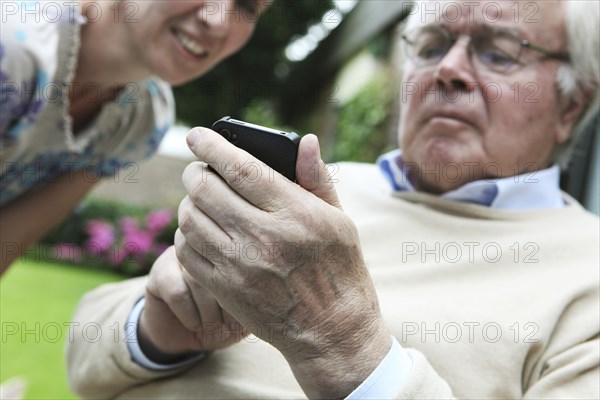 Young woman explaining to a senior citizen how to use a smartphone