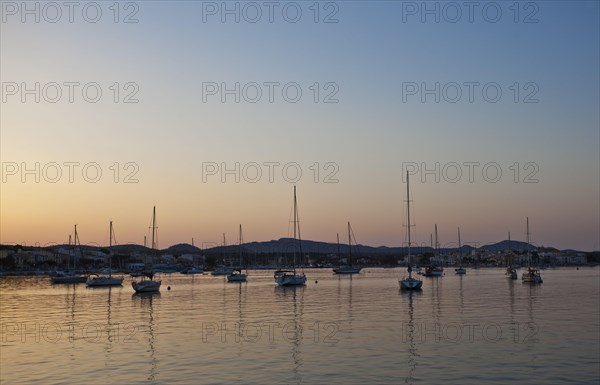 Sailing boats in a harbour at sunset