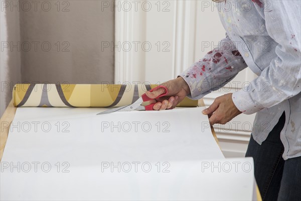 Young woman preparing wallpaper for wallpapering the walls