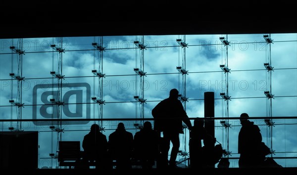 Silhouettes of travellers waiting for trains in the main station building