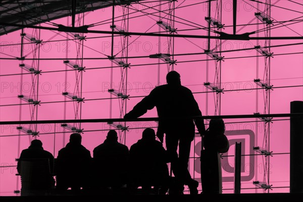 Silhouettes of travellers waiting for trains in the main station building