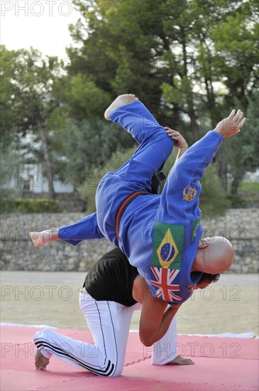 A martial arts instructor is demonstrating a shoulder throw with a student