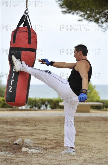 Man is kicking a sandbag during a training session
