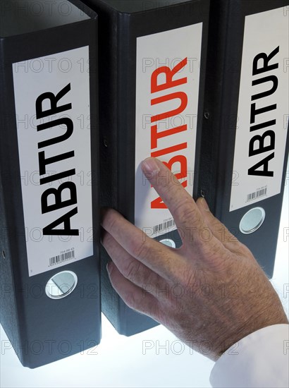 Hand reaching for a file folder labeled 'Abitur'