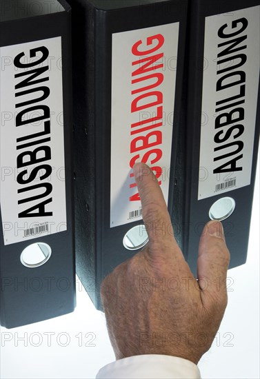 Hand pointing to a file folder labeled 'Ausbildung'