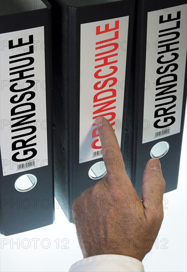 Hand pointing to a file folder labeled 'Grundschule'