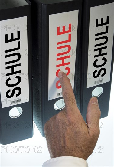 Hand pointing to a file folder labeled 'Schule'