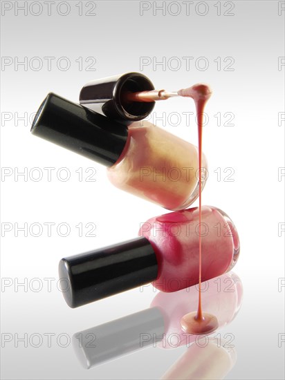 Pink nail varnish dripping from a nail varnish brush balanced on a nail varnish bottle