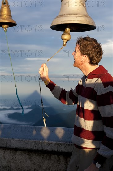 Man ringing a bell at a Buddhist temple