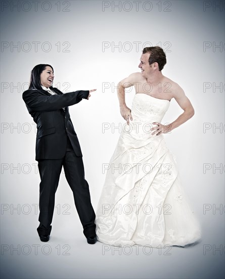 Bride wearing a suit laughing at a groom wearing a wedding dress