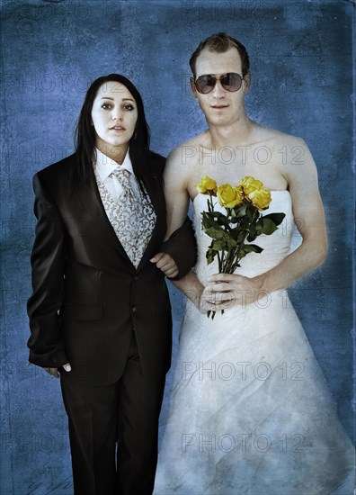 Bride wearing a suit and a groom wearing a wedding dress with sunglasses and yellow roses