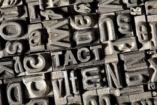 Old lead letters forming the word TACT