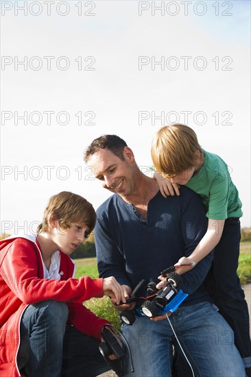 Father tinkering on a remote-controlled model car with his sons