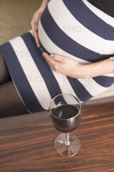 A glass of red wine and a pregnant woman
