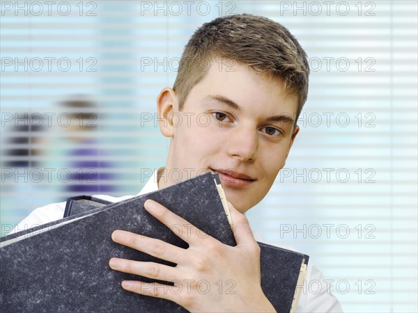 Apprentice or trainee holding files in an office