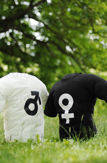 Two T-shirts with the symbols of Mars and Venus on a meadow