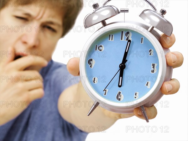Young man holding an alarm clock