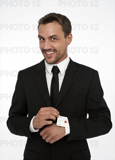 Man wearing a suit pulling an ace of hearts out of his sleeve