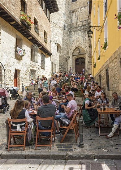 People eating in a street restaurant in front of Church of San Miguel