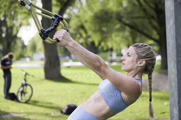 Sporty young woman doing fitness training on the rings
