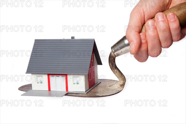 Toy model house on a trowel