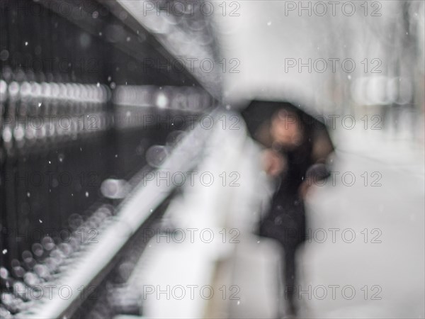 Woman with umbrella walking along a grating