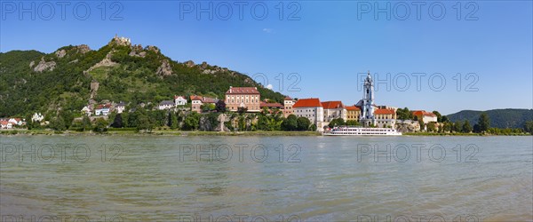 Excursion boat on the Danube in front of the baroque church of Duernstein Abbey