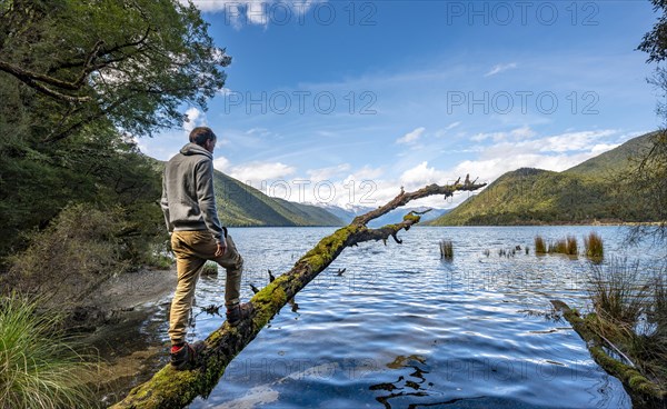 Young man standing on a mossy tree trunk