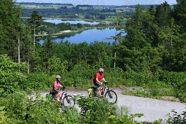 Couple with electric bikes riding above Lake Mattsee