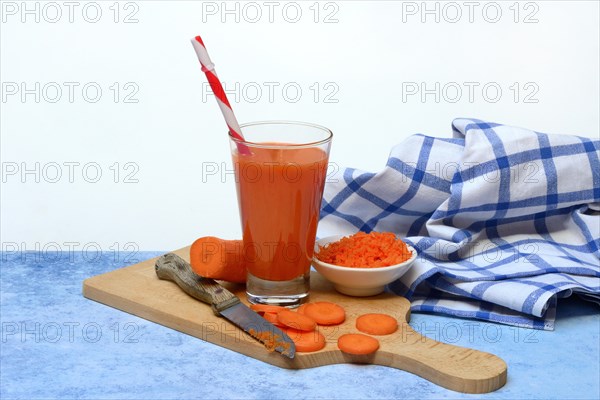 Carrot juice in glass and carrot slices on wooden board