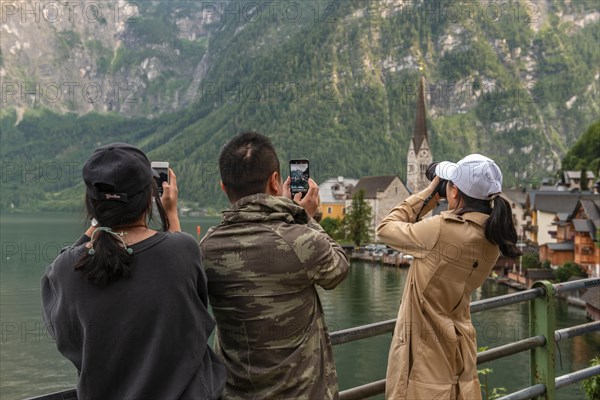 Asian tourists photograph the old town of Hallstatt