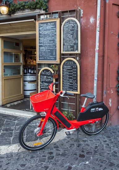 Red JUMP electric rental bike outside Italian restaurant with handwritten blackboard menu