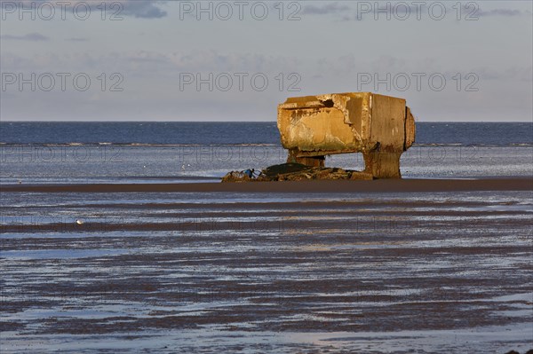 Bunker remains of an anti-aircraft gun position from World War II on the Minsener Oog power station in the evening light