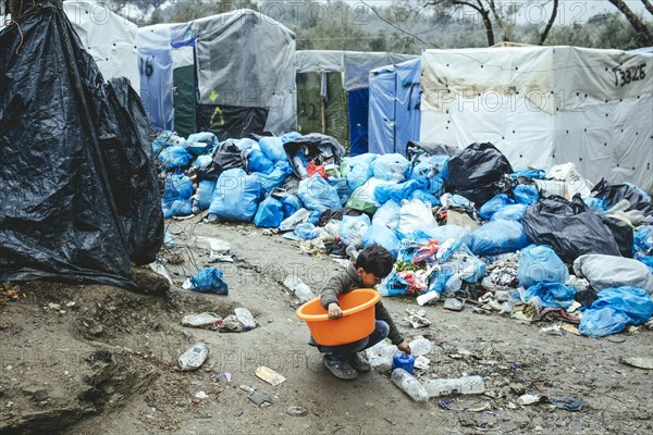 Child collects utensils from the garbage in the refugee camp in Moria