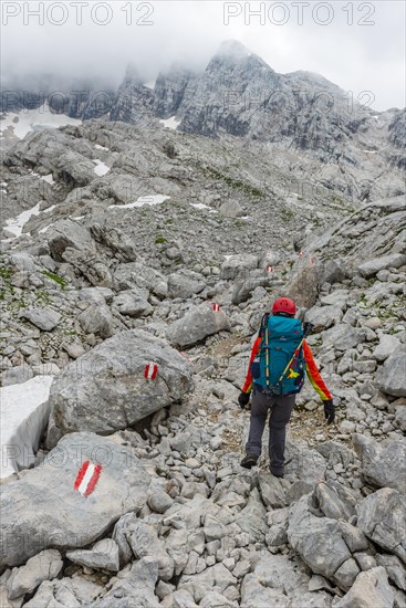 Mountaineer runs through rocky alpine terrain on a marked route