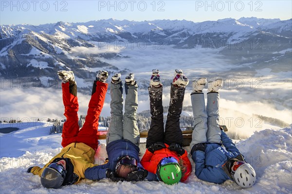 Skiers lie in the snow and stretch their legs in the air
