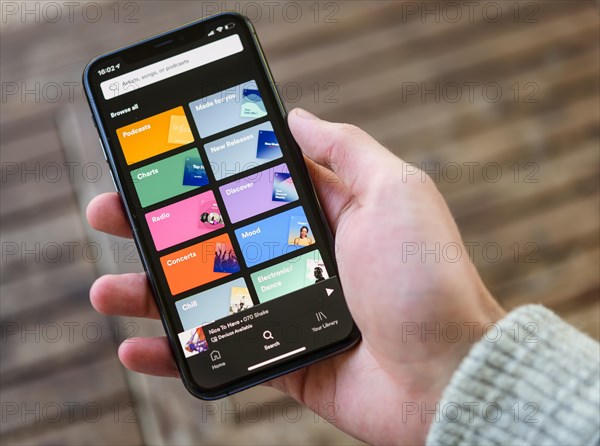 Hand holds iPhone 11 with Spotify App on display