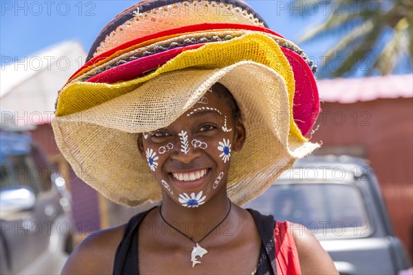 Local saleswoman with traditional face painting sells sun hats, Diego Suarez