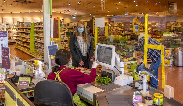 Young woman shopping in a supermarket with face mask, corona crisis