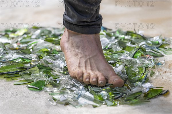 Fakir with foot walking over broken glass
