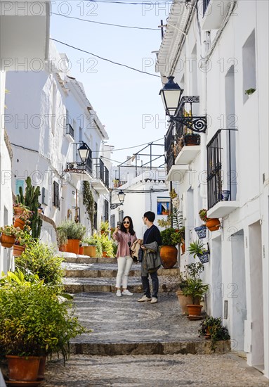 Asian tourists take pictures of themselves in picturesque alleys in the white mountain village of Frigiliana